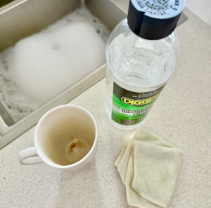 DIGGERS Methylated Spirits bottle beside a coffee-stained mug and cloth on a kitchen benchtop