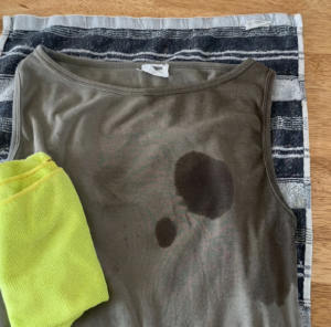 Olive green singlet with stubborn grease and oil stains beside a yellow cleaning cloth